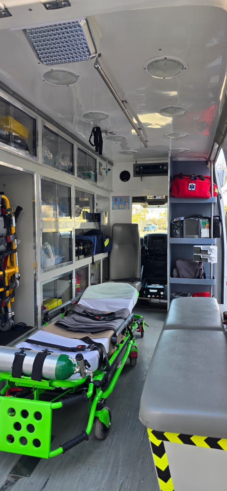 Interior de una ambulancia con camilla, equipo médico y armarios de almacenamiento.