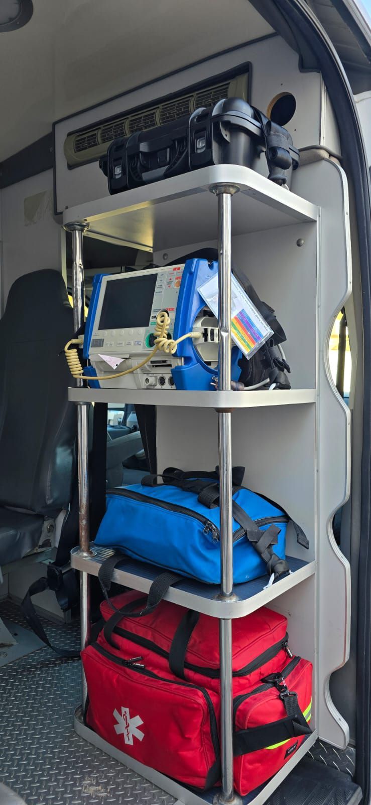 Vista interior de una ambulancia con estantes que contienen equipos médicos y bolsas.