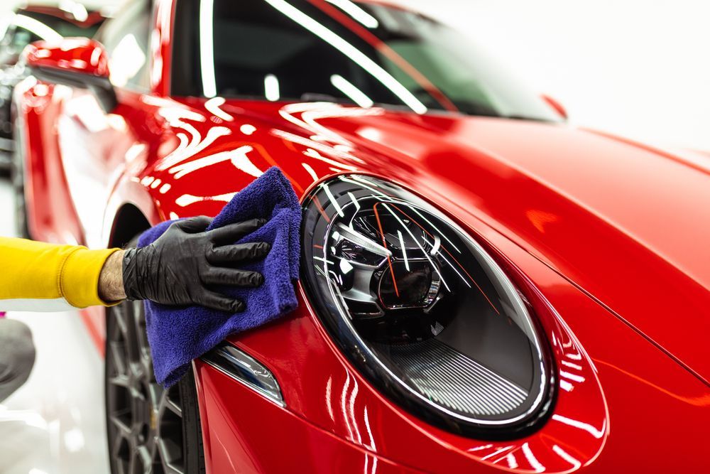 A person is polishing the front bumper of a white car.