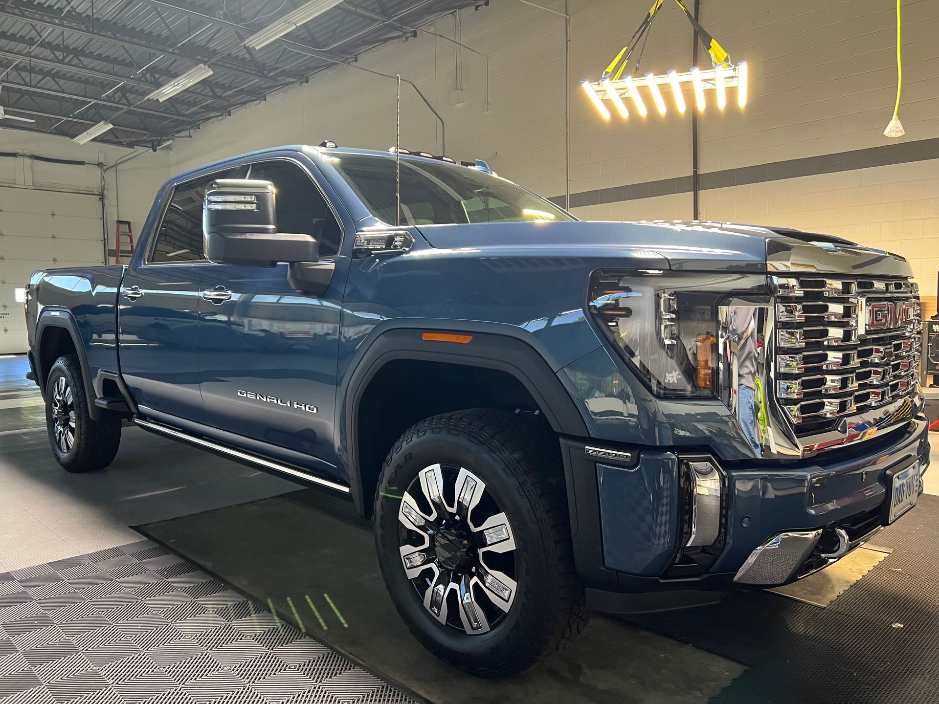 Blue GMC truck in a garage, with chrome accents and bright overhead lights.