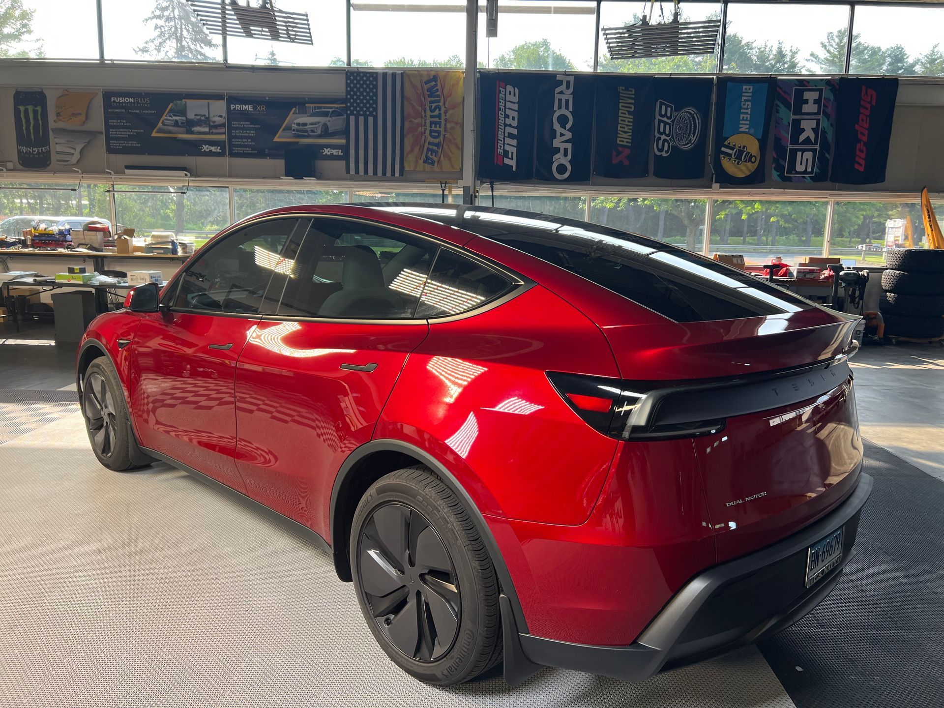 Red Tesla Model Y in a garage, angled view.