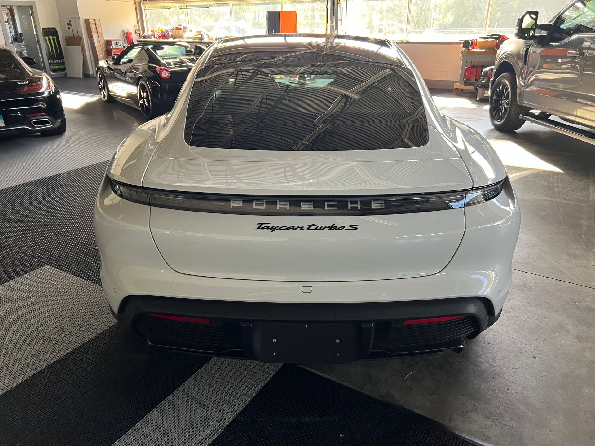 A tesla model 3 has a sunroof with a tree in the background.