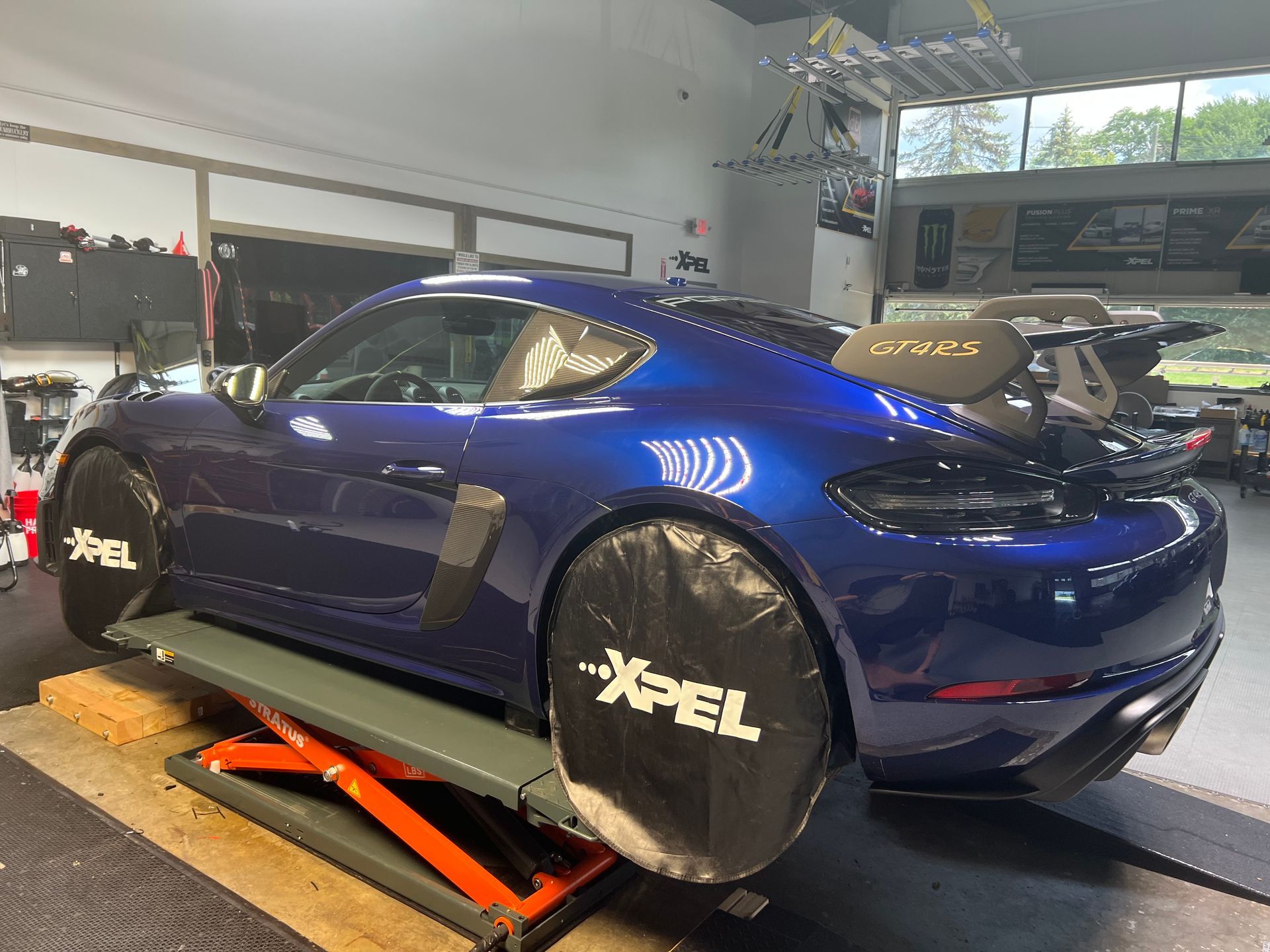 Blue Porsche sports car on a lift in a garage, with wheel covers.