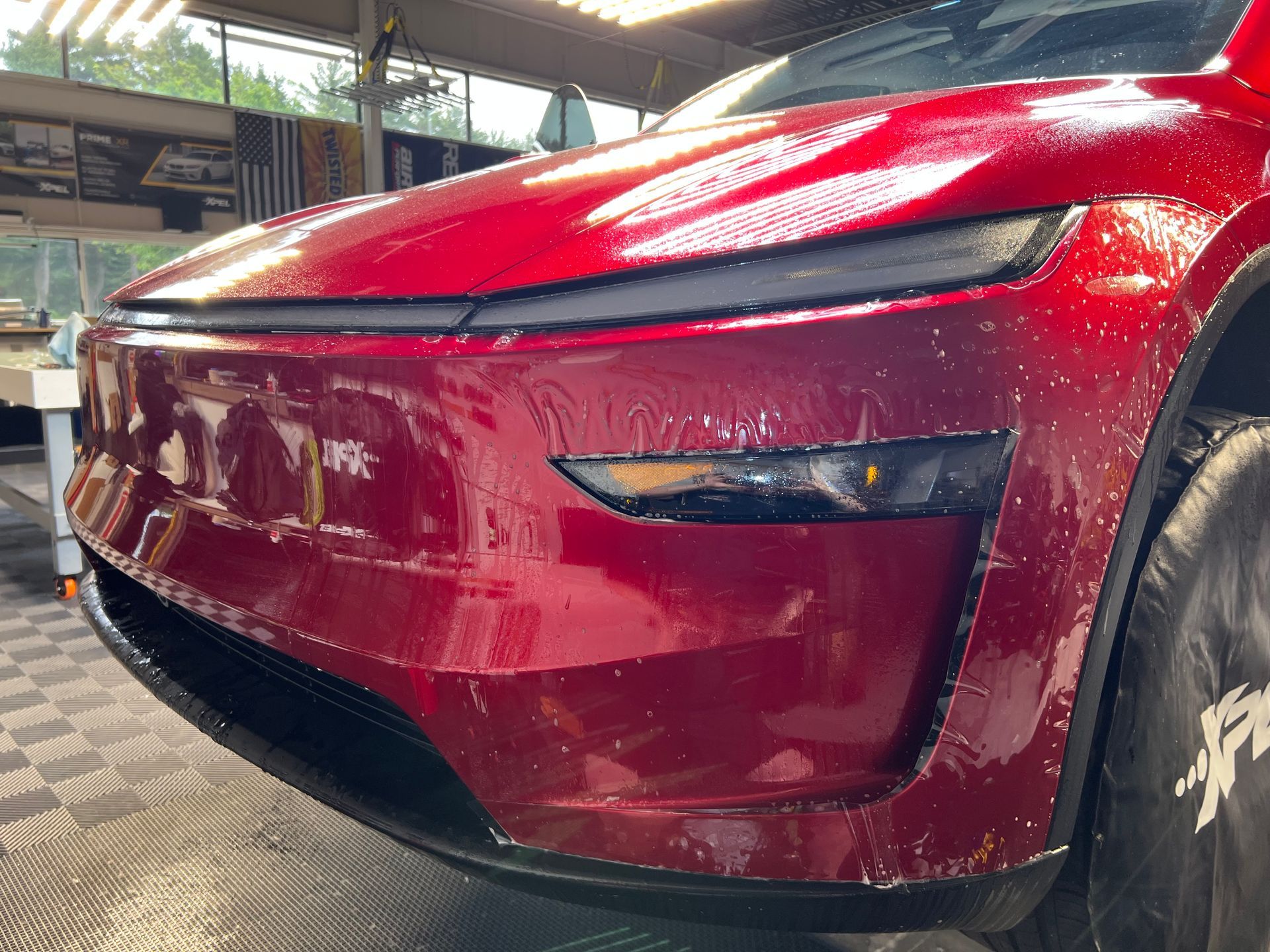 A man is sitting on a stool in front of a car.