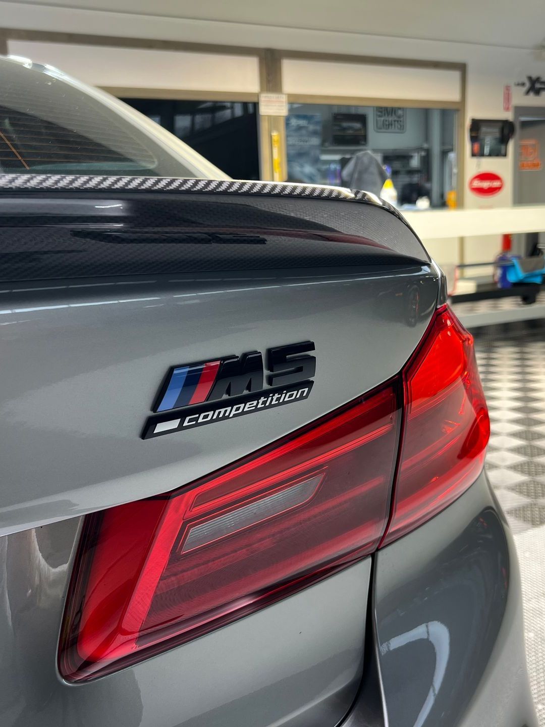 A person wearing black gloves is polishing the hood of a red car.