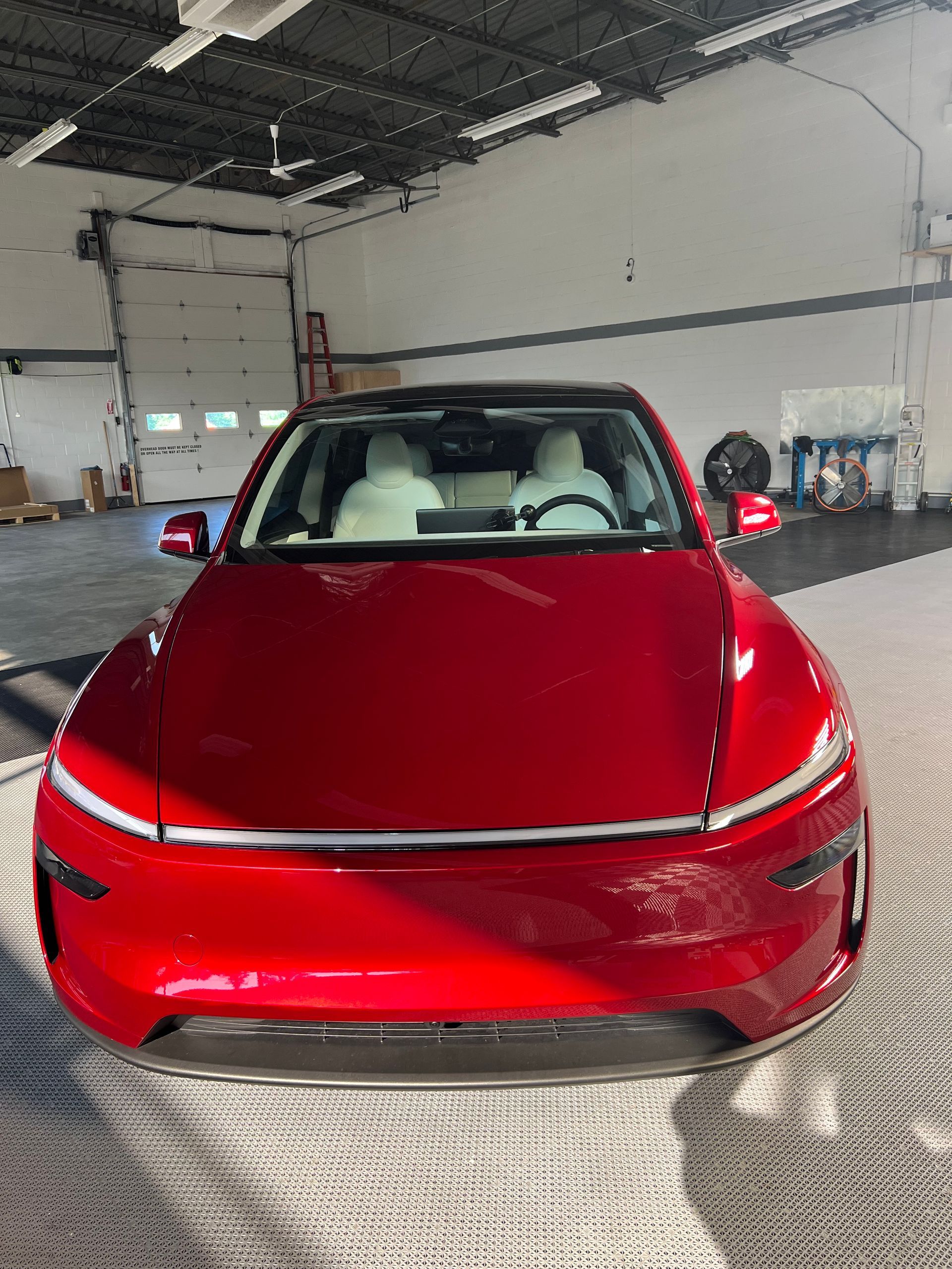 A red tesla model s is parked in a garage.