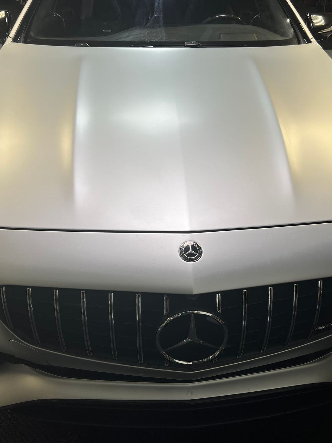 A white mercedes with a black grille and hood