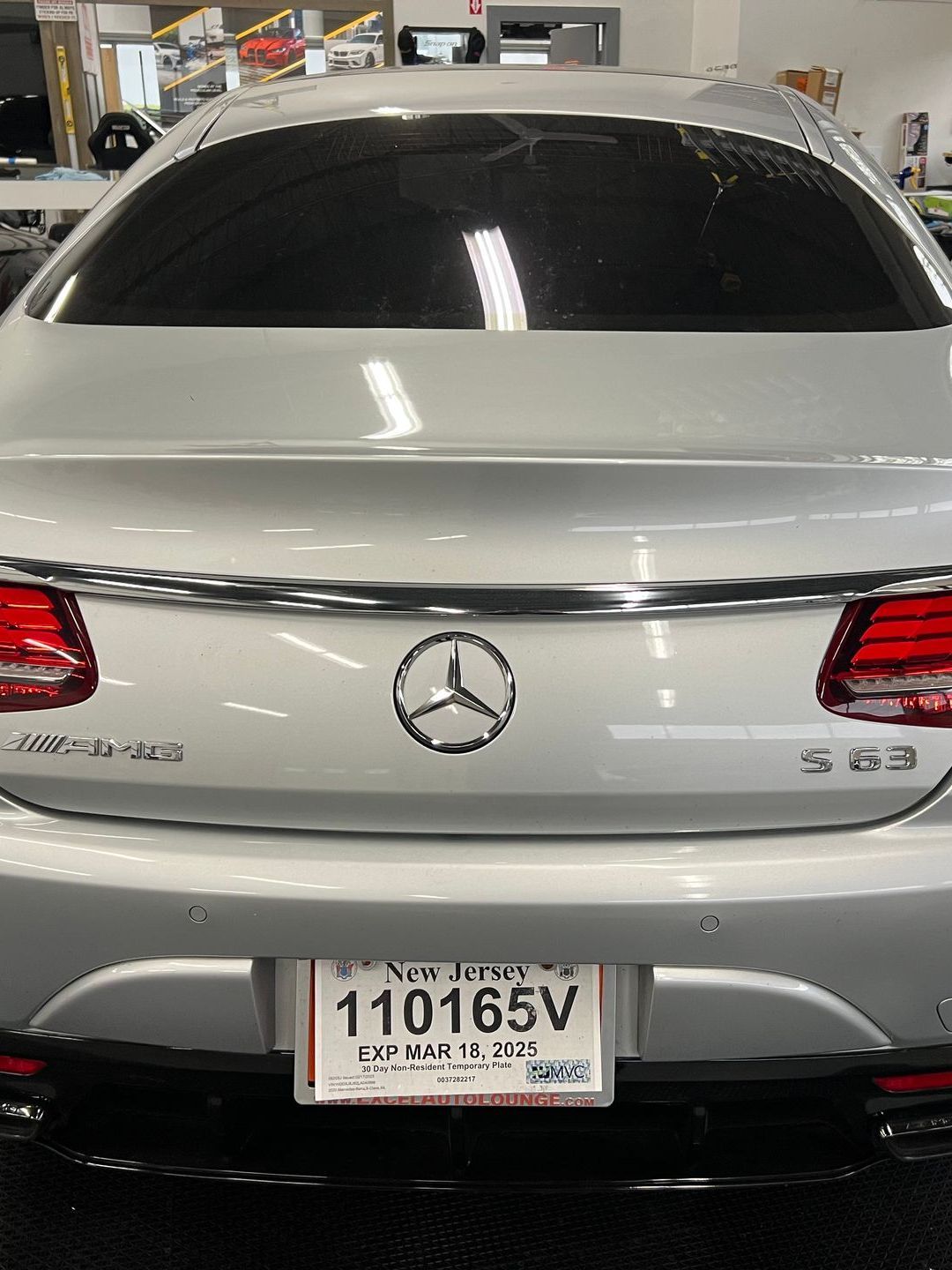 The back of a silver mercedes benz with a license plate that says 110165v