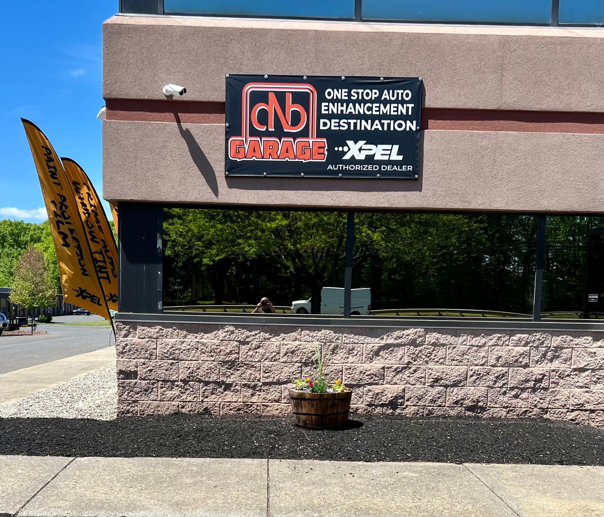 A tesla model 3 has a sunroof with a tree in the background.