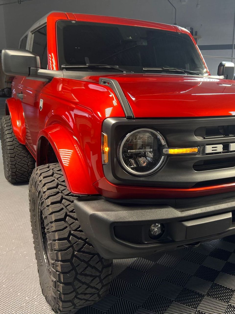 A red ford bronco is parked in a garage.