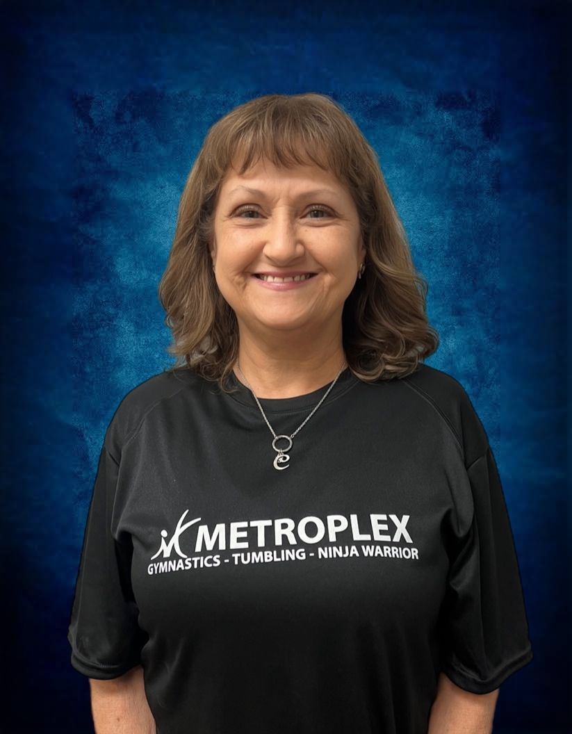 Woman in black shirt smiling, wearing a necklace. The shirt has 