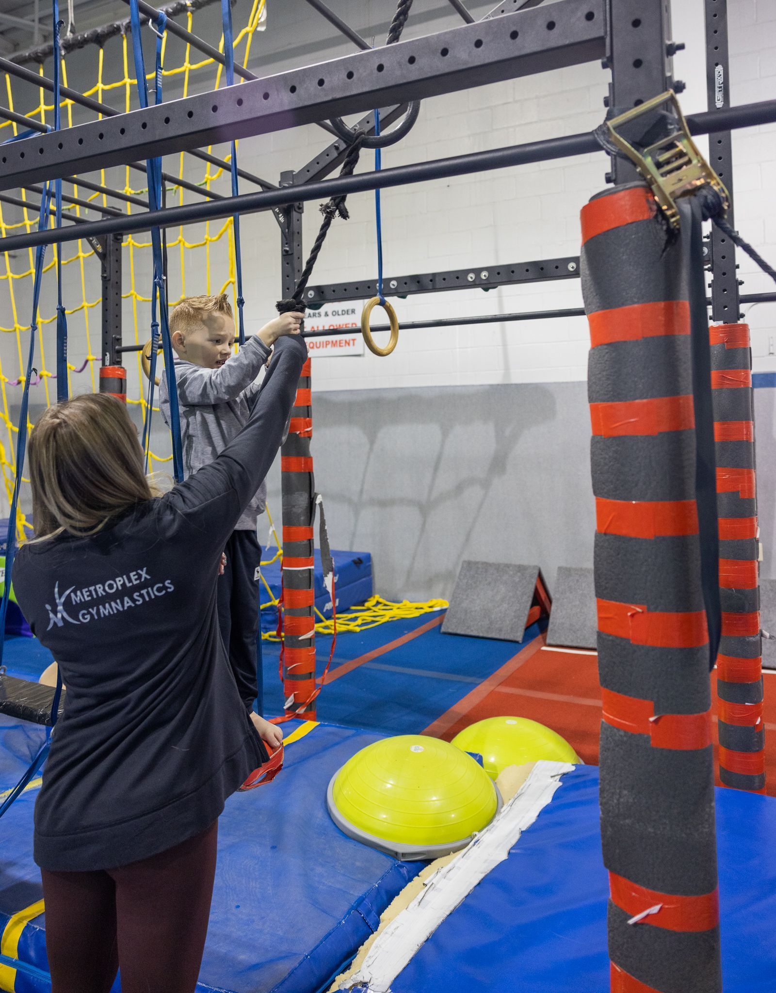 A child on an obstacle course, being assisted by a person.