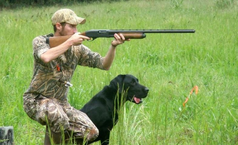 A kitchen in an RV featuring wood cabinets, a dark granite-style countertop, a stainless sink, and a dark mosaic backsplash.