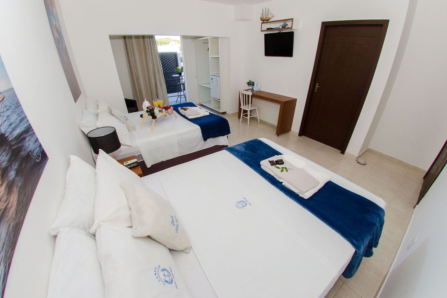 Um quarto de hotel com duas camas, uma escrivaninha e uma televisão.