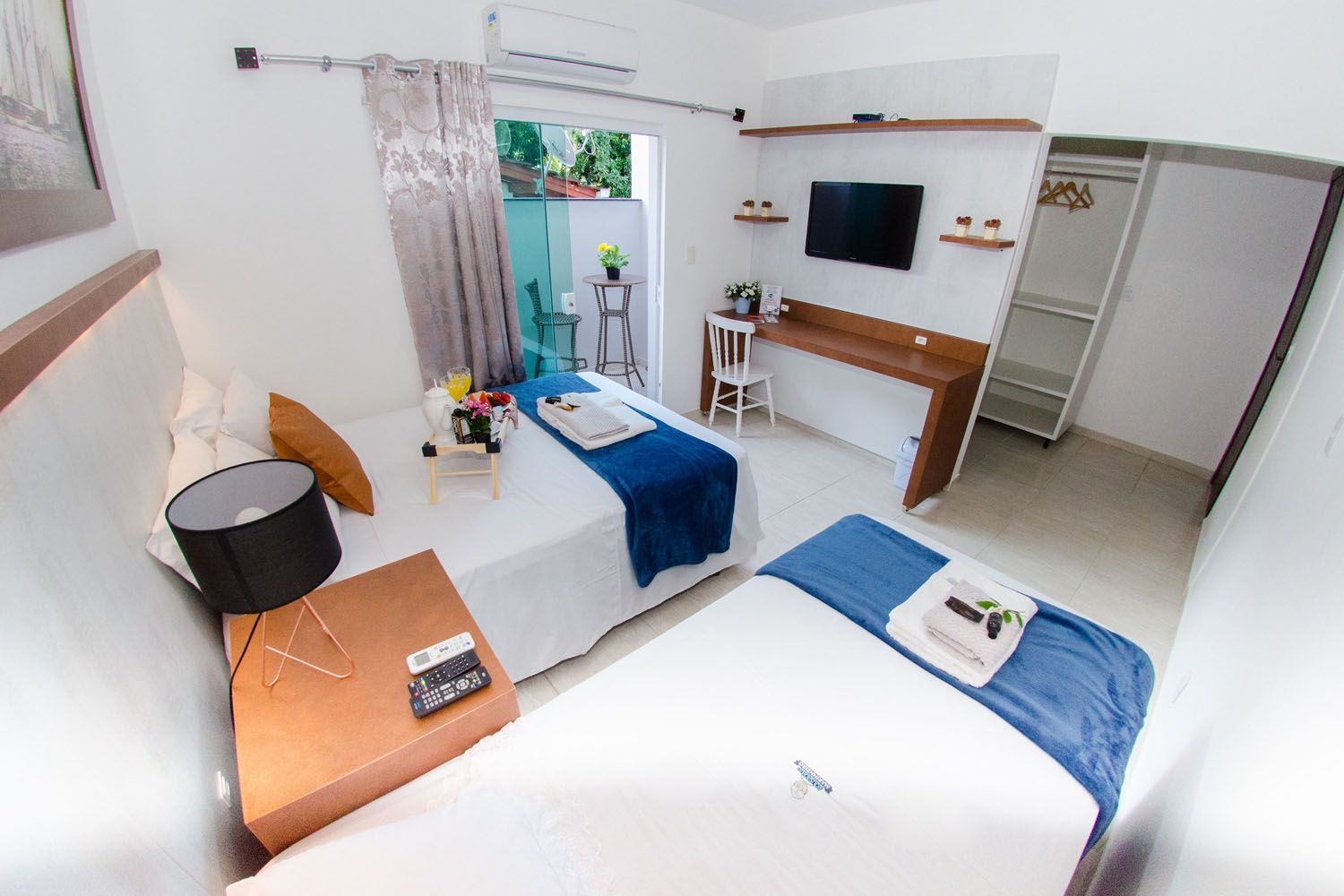 Um quarto de hotel com duas camas, uma escrivaninha e uma televisão.