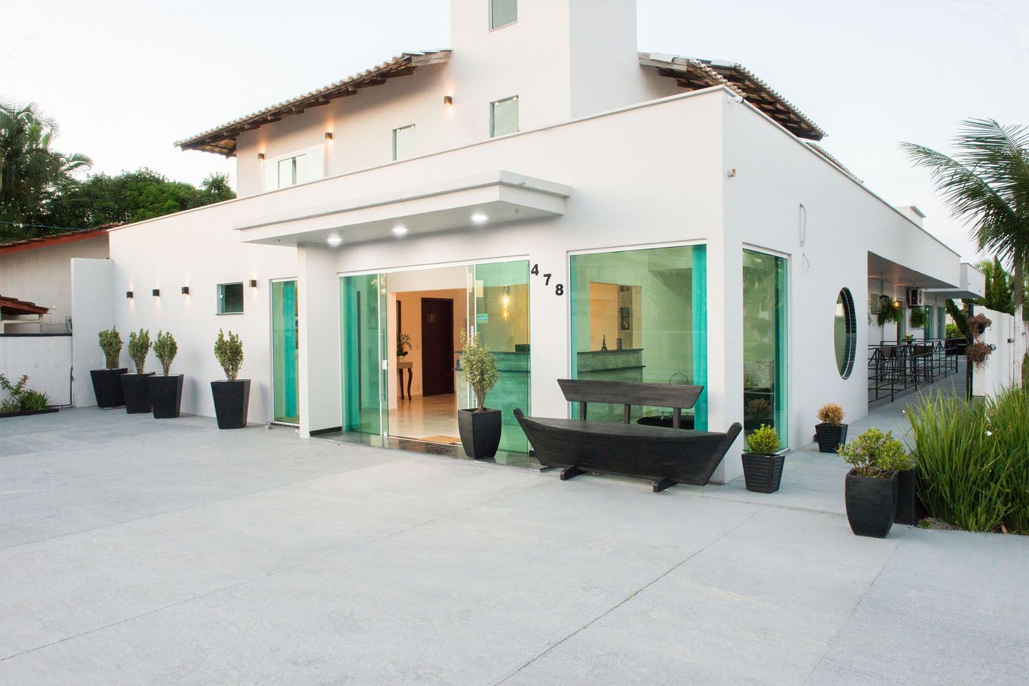 Uma grande casa branca com muitas plantas em vasos na frente dela