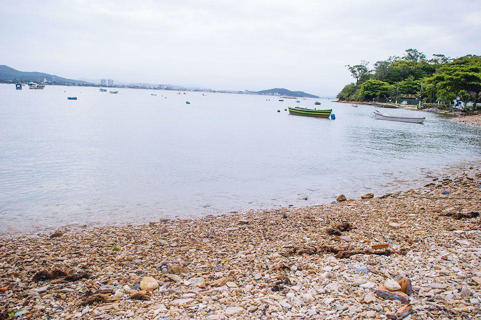Um barco está flutuando na água perto de uma praia rochosa.
