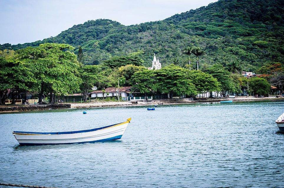 Um barco flutua em um corpo d'água com montanhas ao fundo