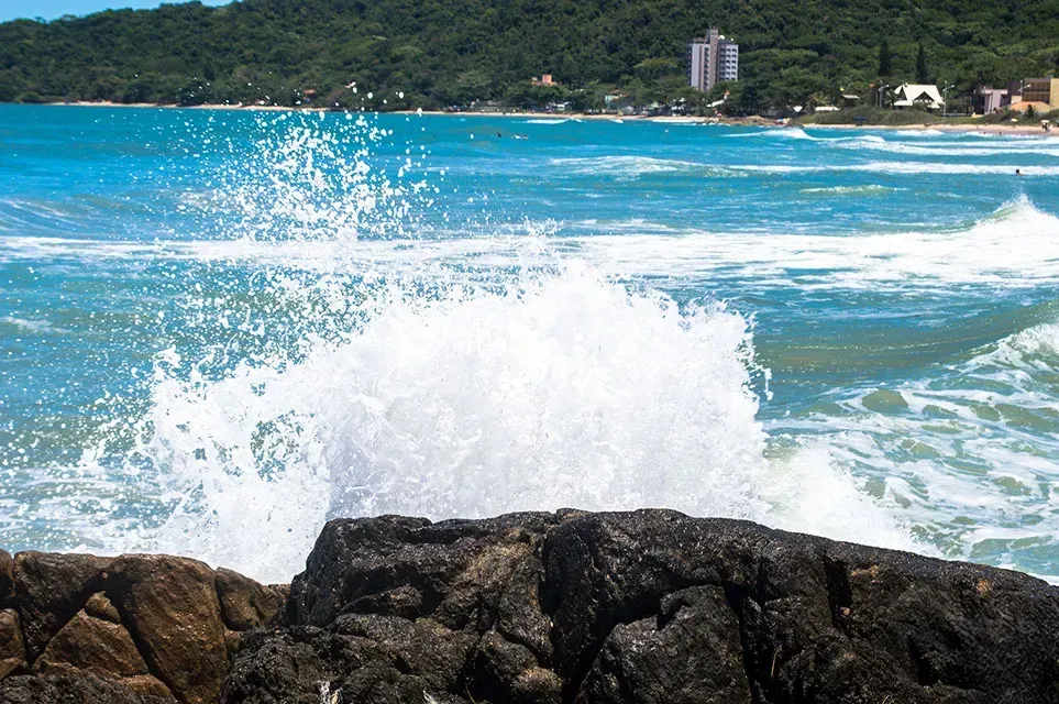 As ondas estão quebrando contra as pedras na praia.