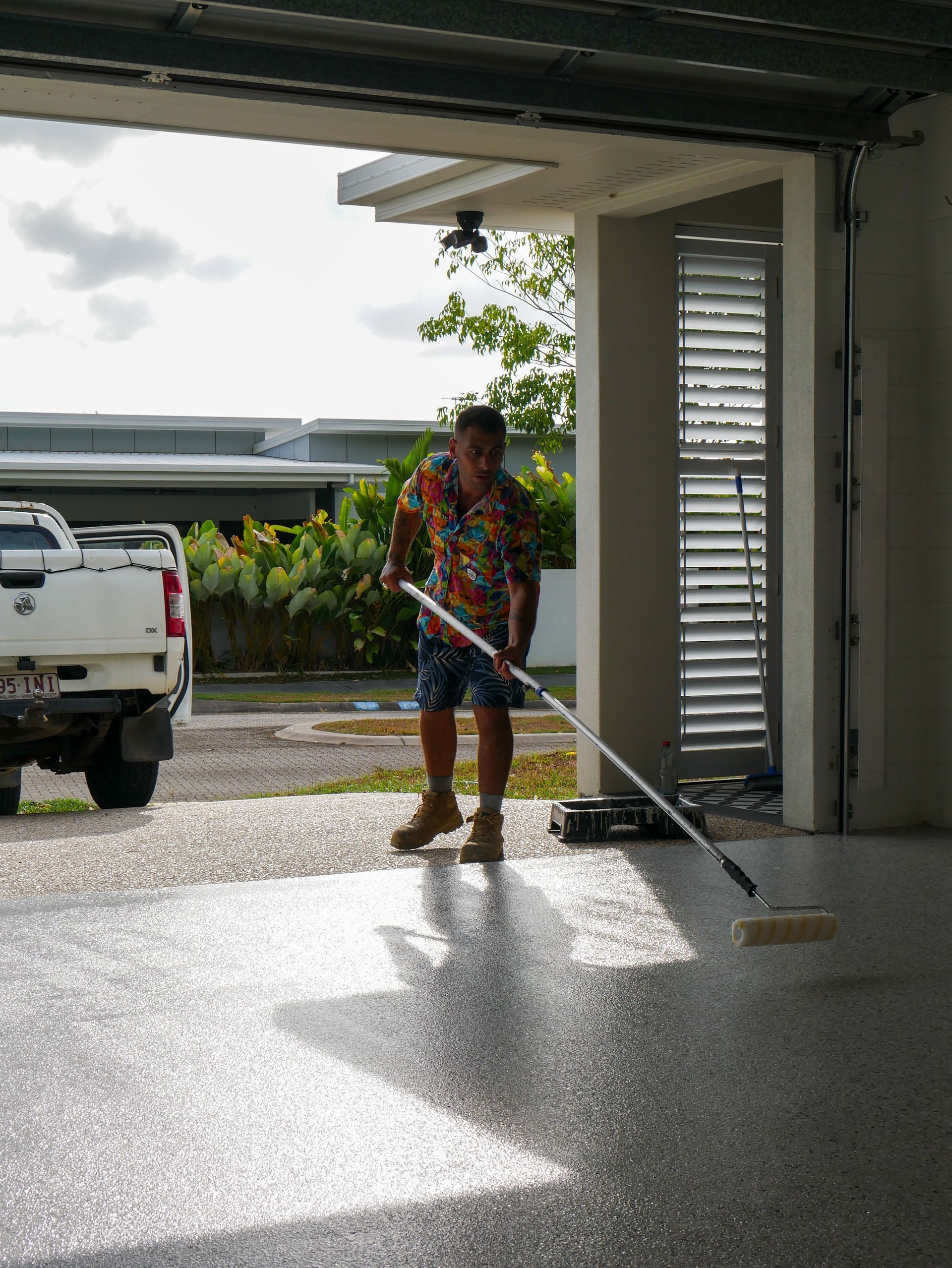 A man is cleaning a garage floor with a broom.