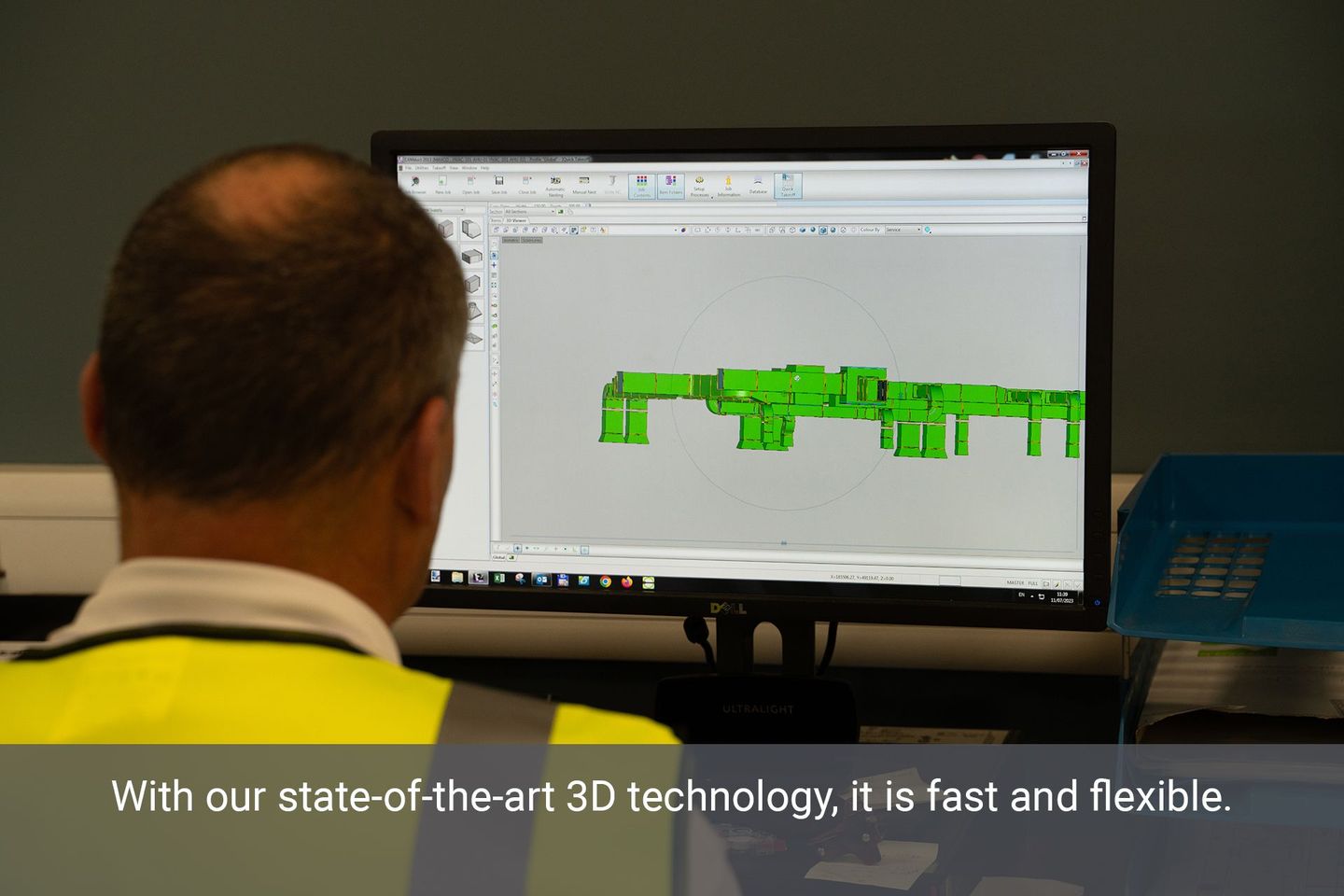 An A.C. Manfufacturing staff member in a high-vis vest looking at a computer screen with a 3d drawing on the screen