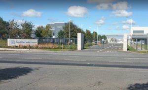 an outside view of Bristol-Myers Squibb, fences and gates and a large sign saying Bristol-Myers Squibb