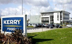An outside view of Kerry Foods Factory and cars parked outside and a large Kerry Foods sign