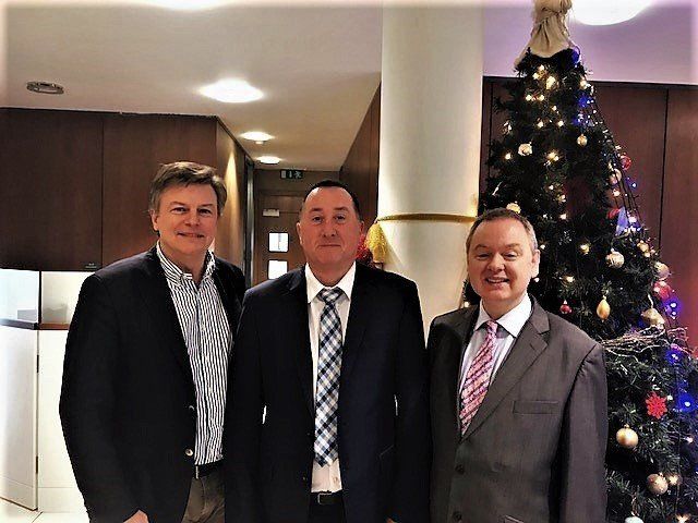 Three company directors standing in front of a pillar and Christmas tree