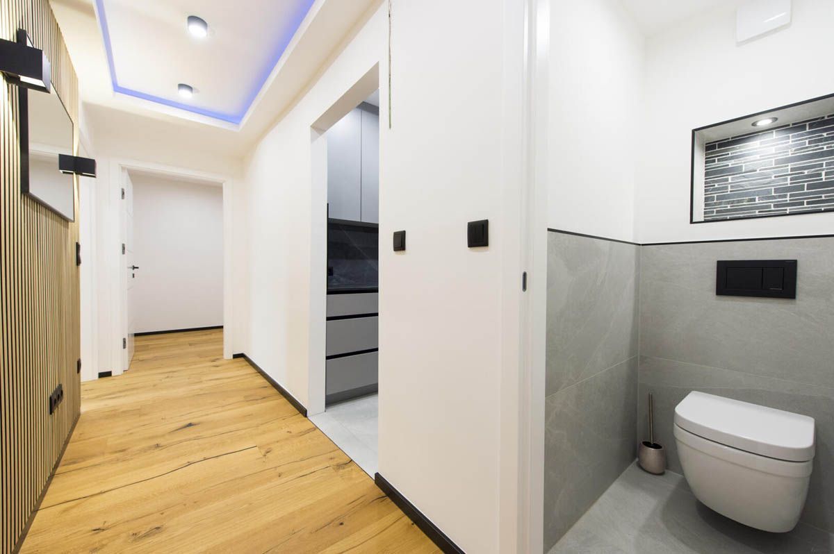 Flur mit Holzboden, Gästetoilette mit weißer Toilette und Schrankeingang.