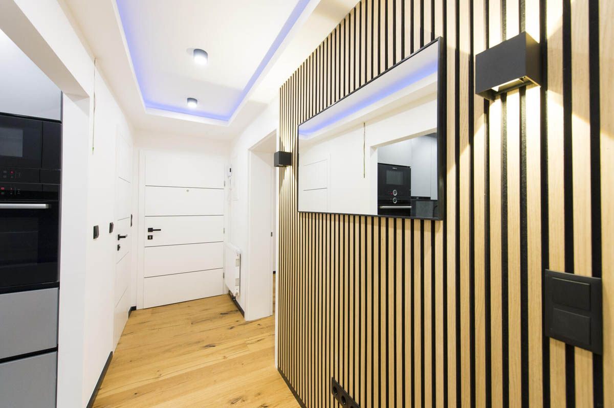 Flur mit Akzentwand aus Holzlatten, Einbauleuchten und Holzboden.