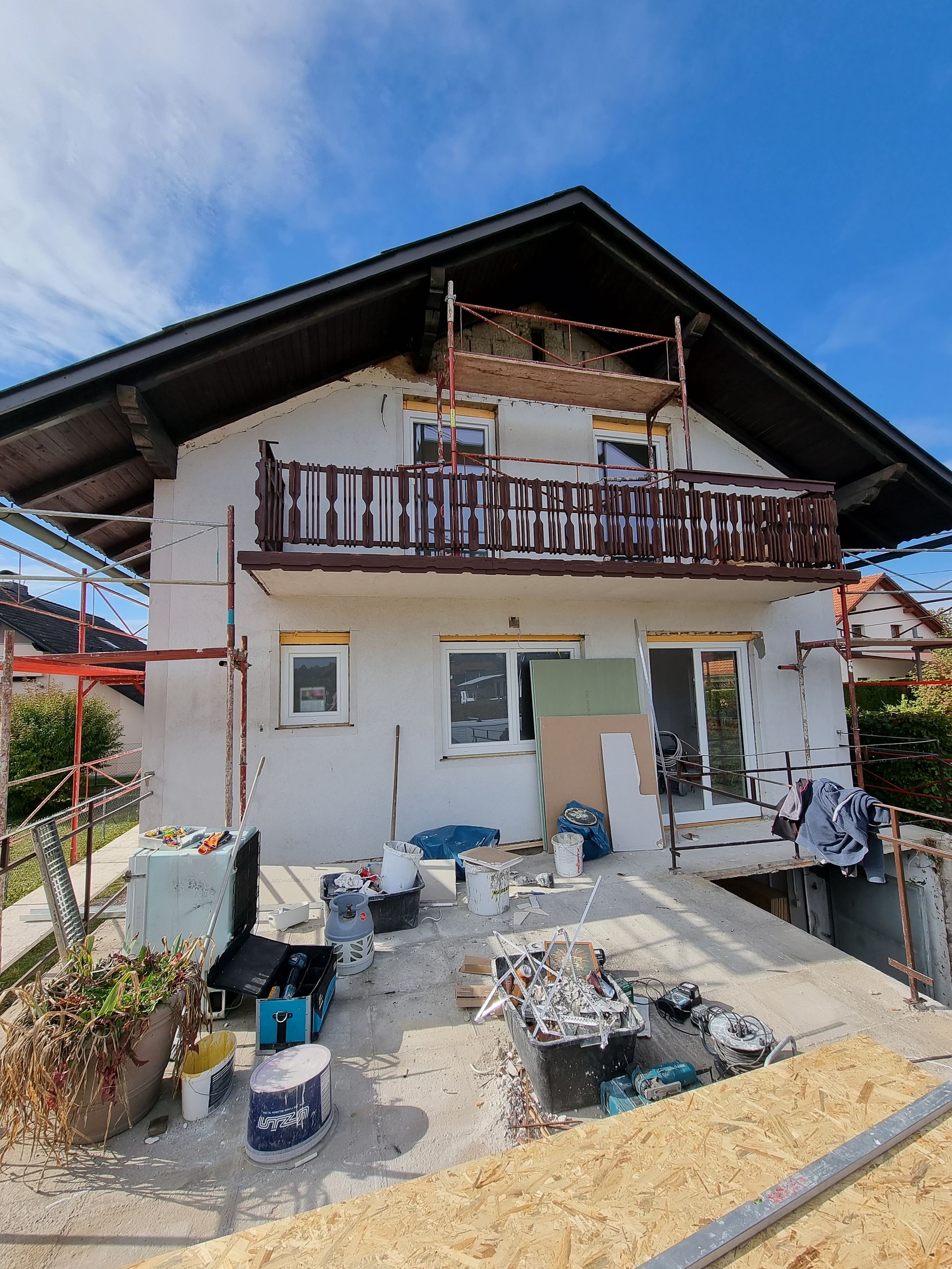 Haus im Umbau mit Gerüsten, Schutt und Baumaterialien im Freien.