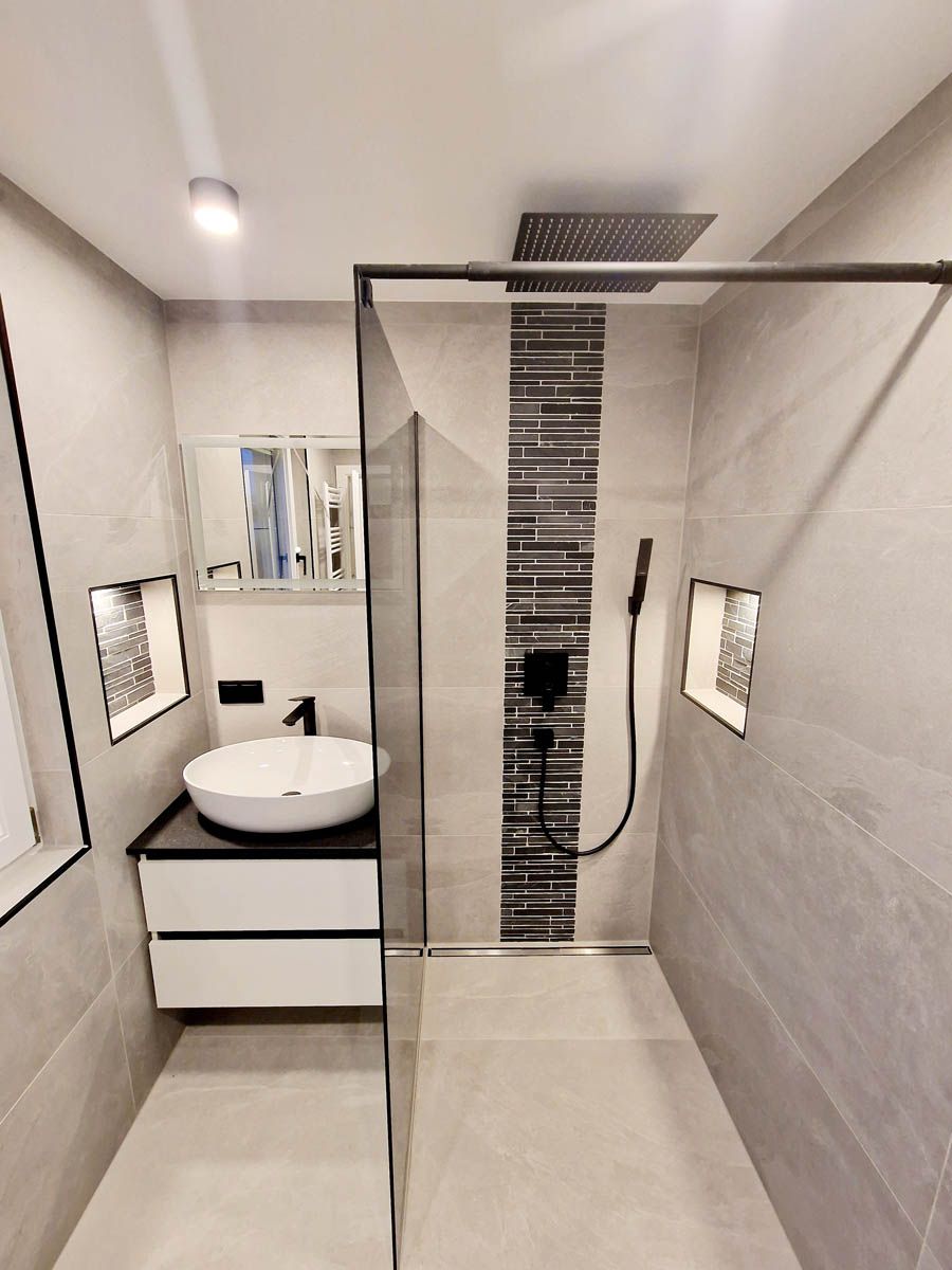 Modernes Badezimmer mit Dusche, Waschtisch und Fliesen in neutralen Tönen. Schwarze Armaturen, Glasduschtür.