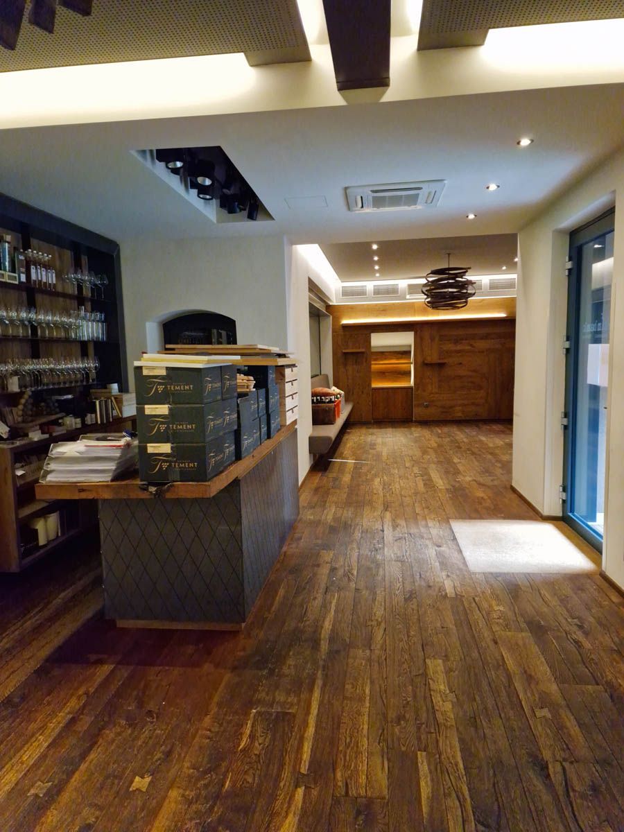 Innenansicht eines Ladens mit Holzböden und Ausstellungsregalen. Theke und Regale mit Waren.