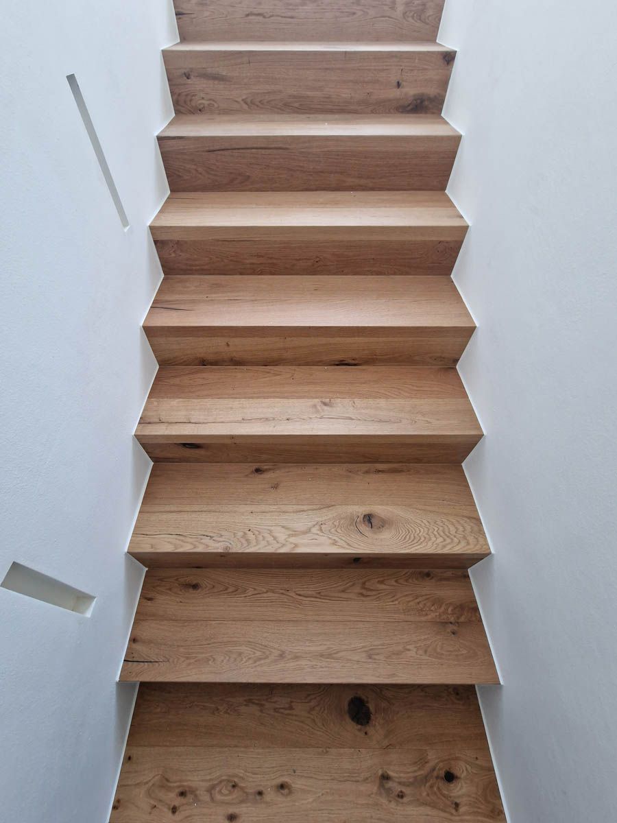 Holztreppe mit weißen Wänden.