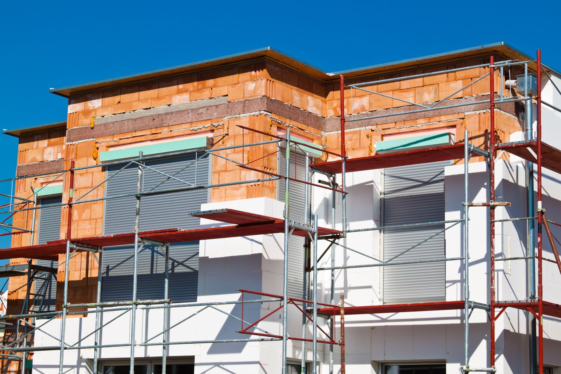 Haus im Bau mit Gerüst, rotem Backstein, Wärmedämmung