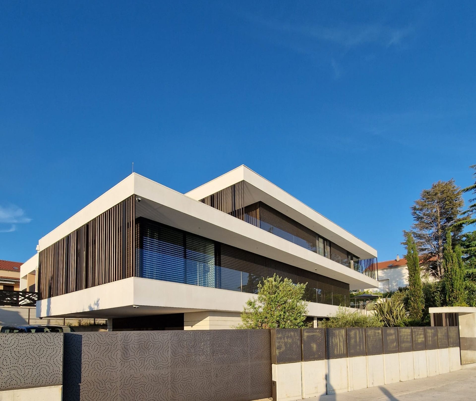 Modernes Haus aus weißem und dunklem Holz unter einem klaren blauen Himmel.