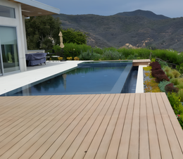 Swimming pool and wooden deck with a view of mountains and green landscape.
