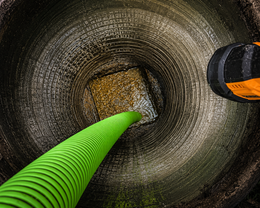 Looking down a brick chimney with a green hose and an orange tool inside