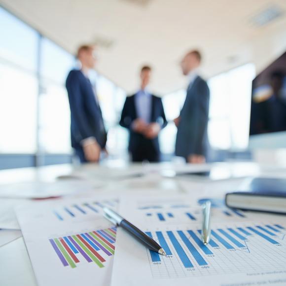 business men at a conference table with graphs