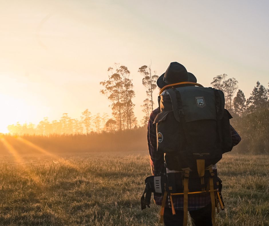 man hiking with backpack at sunset.
