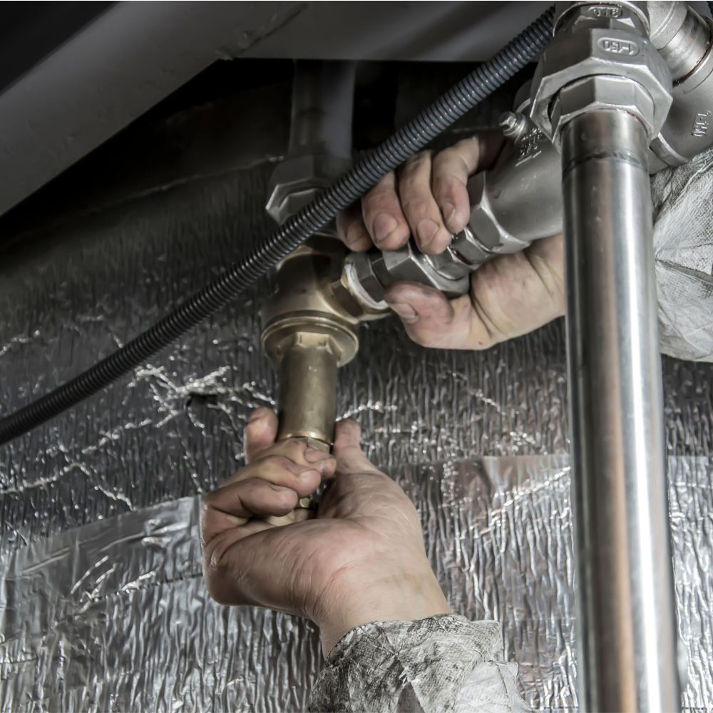 TRW Technician fixing a leaky pipe with a wrench.