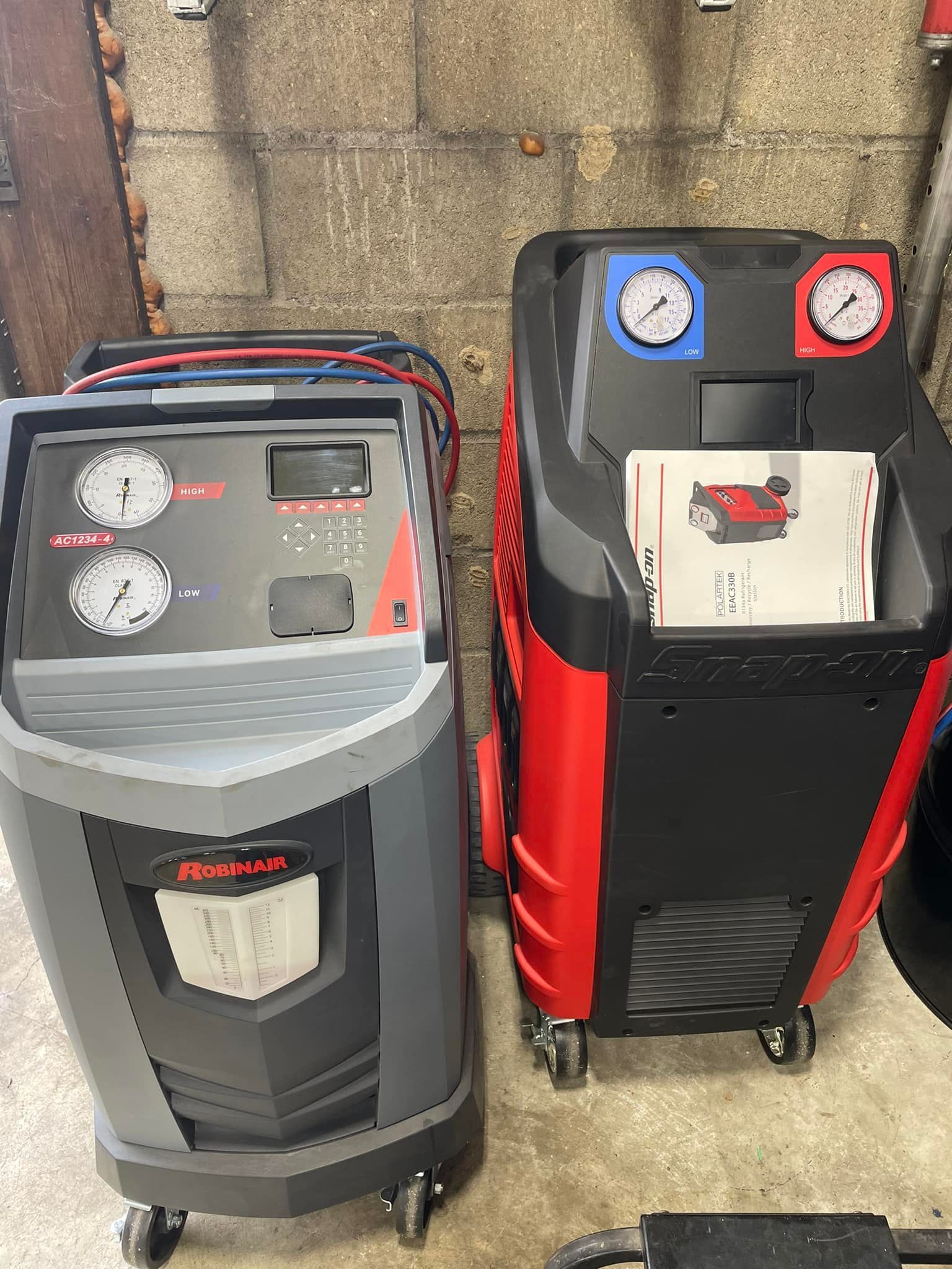 Two air conditioning machines are sitting next to each other in a garage.