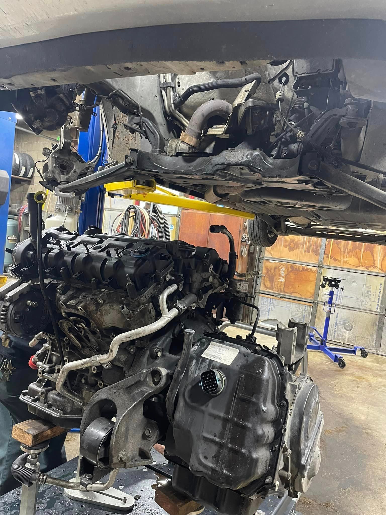 A car engine is being dismantled in a garage.