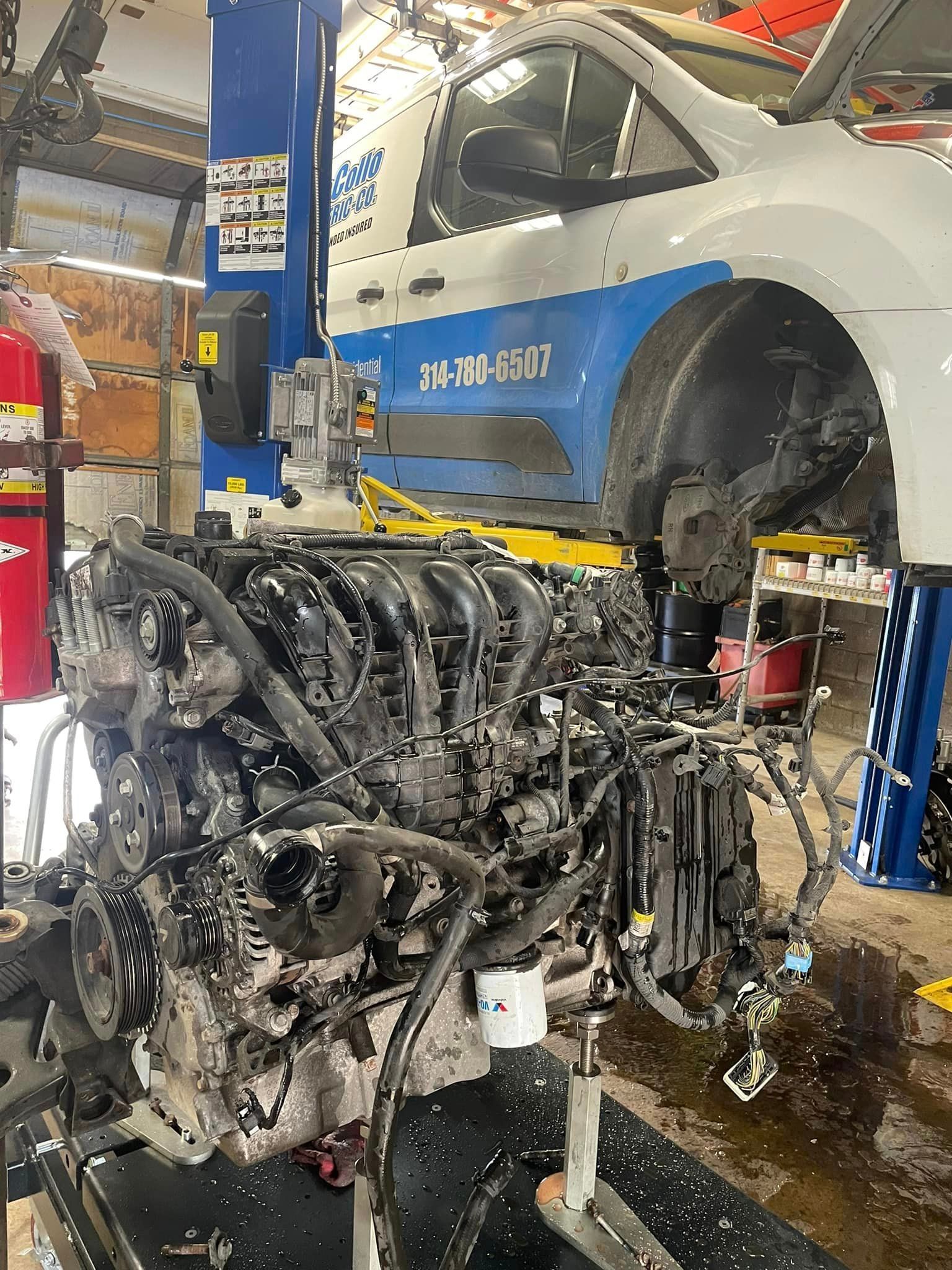 A car engine is being removed from a van in a garage.