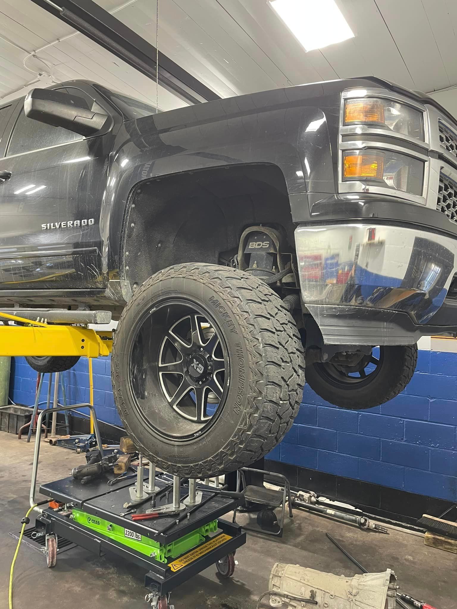 A truck is sitting on top of a lift in a garage.