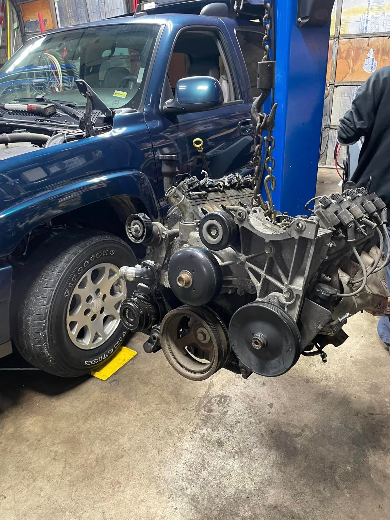A blue truck is being dismantled in a garage.