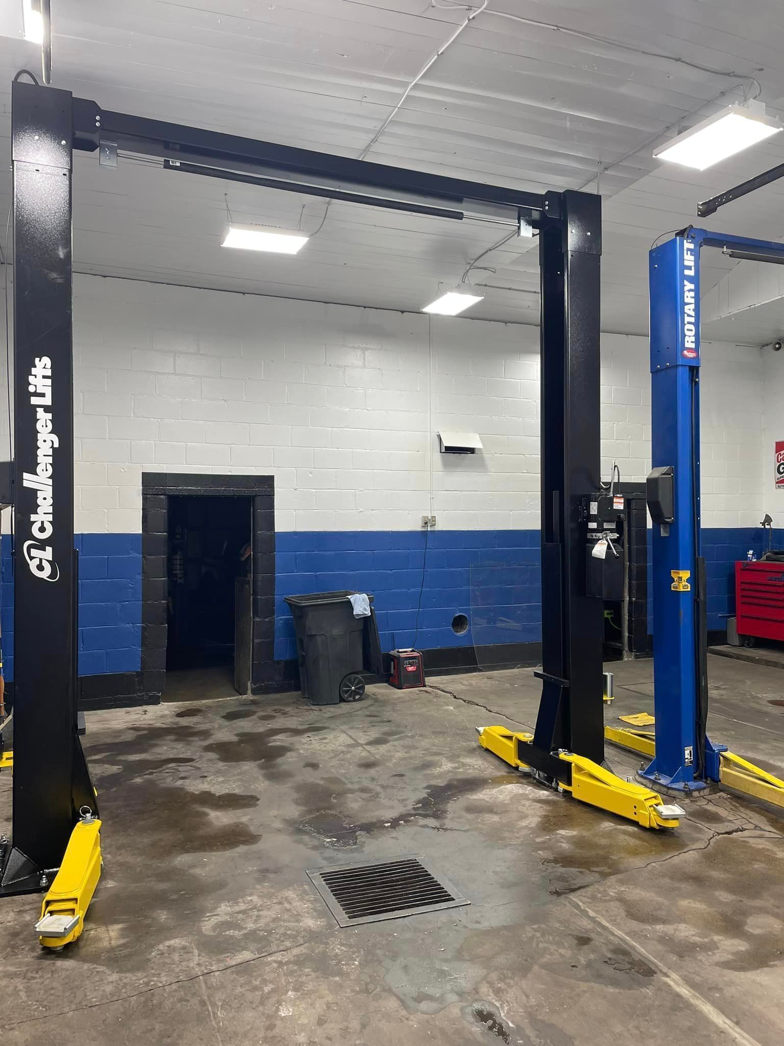 Two hydraulic lifts are sitting in a garage next to each other.