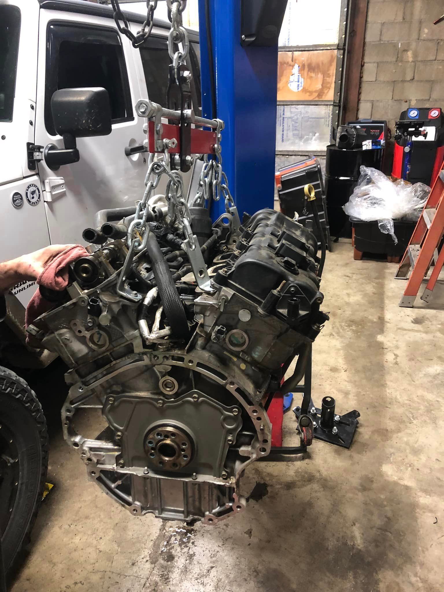 A jeep engine is being worked on in a garage.