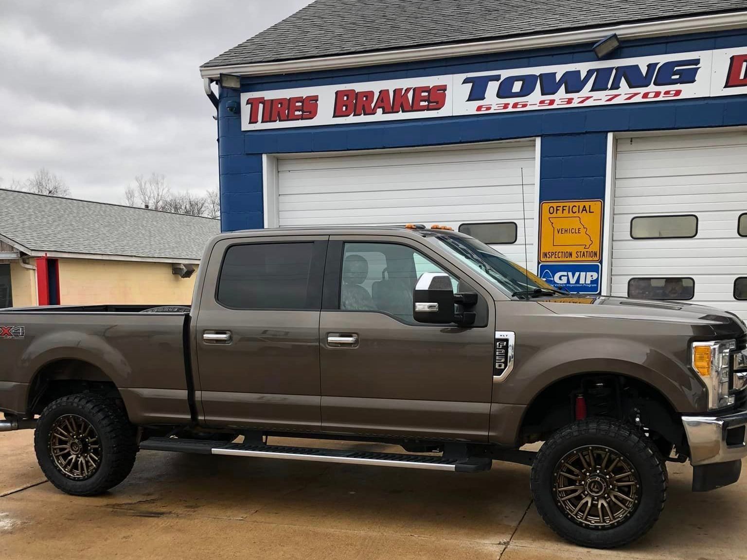A pickup truck is parked in front of a towing company.