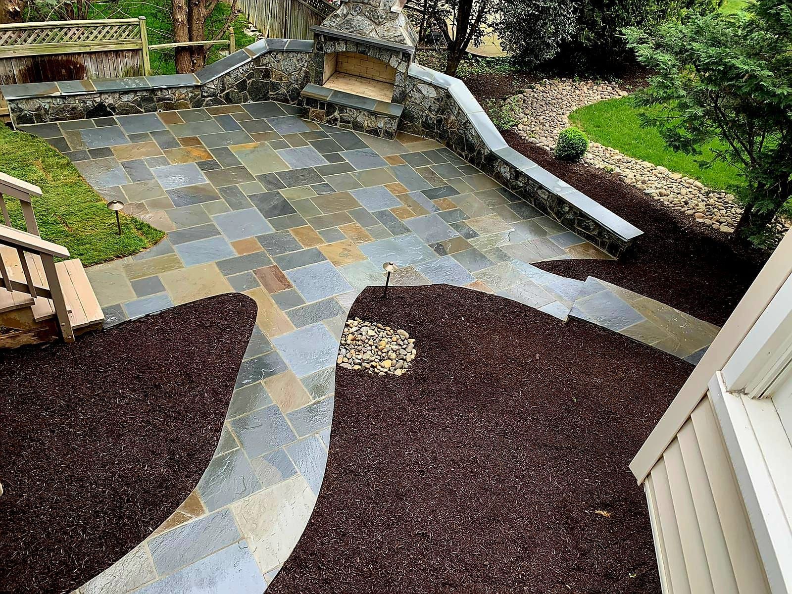 An aerial view of a patio with a fireplace and a bench.